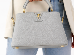 louis-vuitton-grey-leather-top-handle-handbag-held-by-woman-with-gold-lv-logo-white-background
