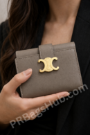 taupe-leather-wallet-with-gold-logo-clasp-held-in-woman-hand-premium-inspired-compact-wallet