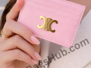 pink-leather-card-holder-wallet-with-gold-logo-held-in-female-hand-minimal-style