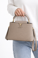 louis-vuitton-m24729-grey-leather-top-handle-handbag-held-in-woman-hand-with-adjustable-strap