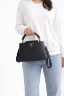 louis-vuitton-capucines-bb-black-leather-top-handle-handbag-held-by-woman-white-background