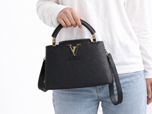 louis-vuitton-capucines-bb-black-leather-top-handle-handbag-held-by-woman-white-background