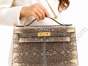 snake-print-top-handle-bag-held-by-woman-in-white-blazer-with-gold-hardware-on-white-background