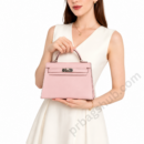 pink-kelly-style-top-handle-handbag-held-by-woman-in-white-dress-with-silver-hardware-white-background